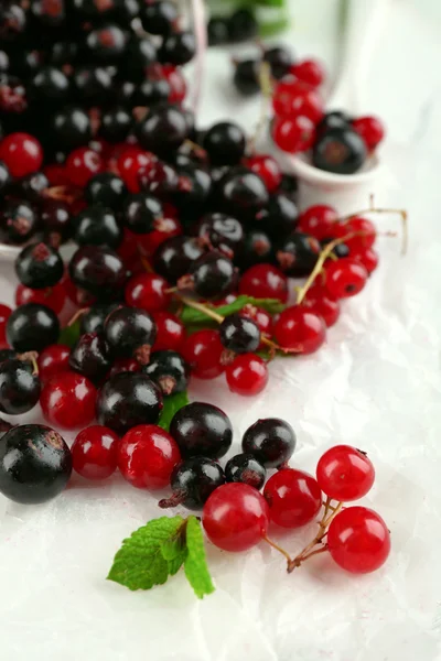 Ripe forest berries in glass bowl on light background