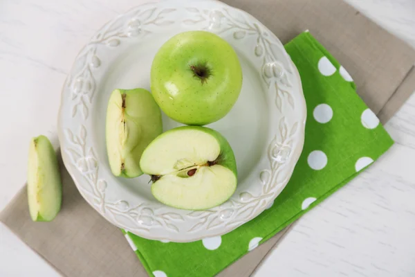 Green apples in plate on table with napkin, closeup — Stock Photo, Image