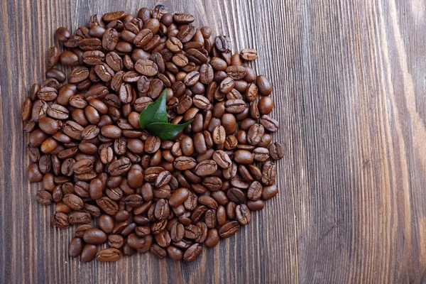 Kaffeebohnen mit Blättern auf Holztisch aus nächster Nähe — Stockfoto