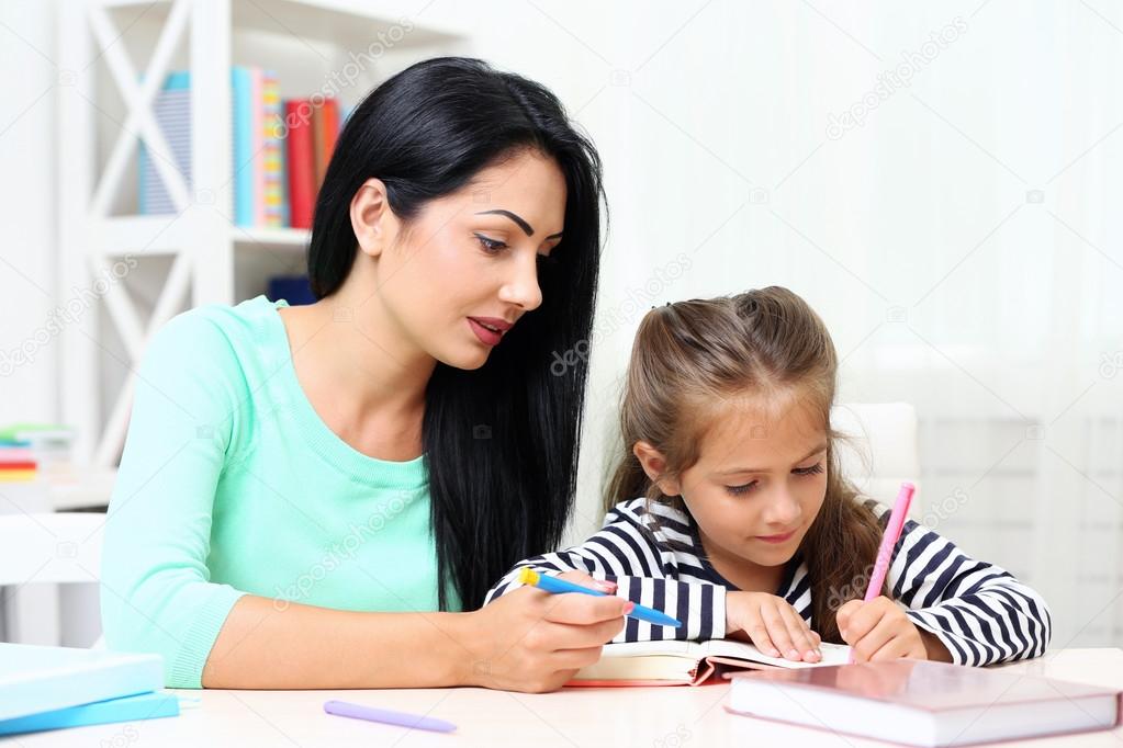 School girl doing homework with mother 