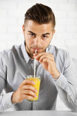 Genç adam portakal suyu içiyor.