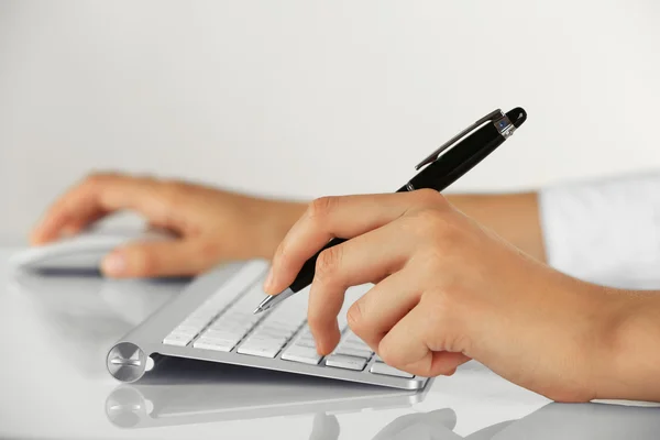 Female hands holding pen and computer mouse on light background — Stock Photo, Image