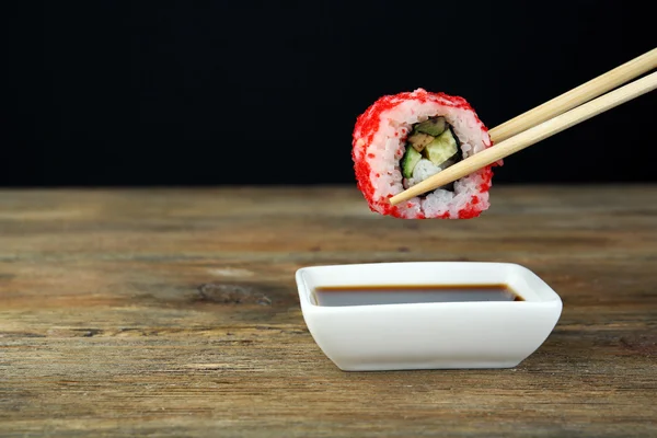 Dipping roll in sauce on dark background — Stock Photo, Image