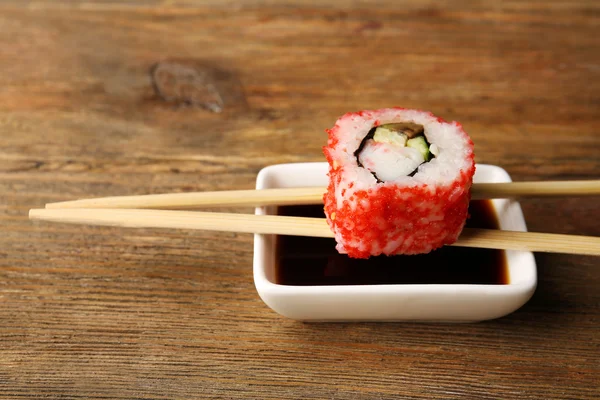 Rollo con salsa y palos en la mesa de madera de cerca — Foto de Stock