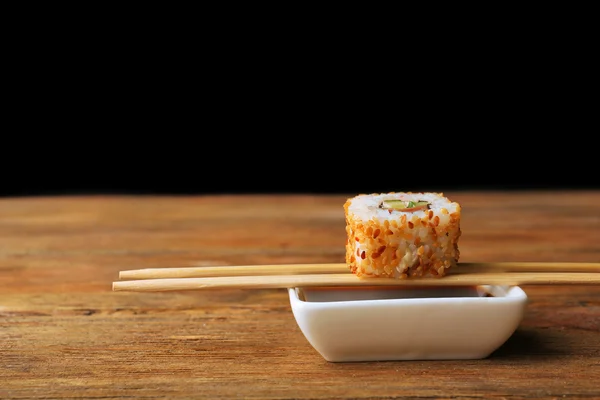 Rollo con salsa y palos de madera sobre fondo oscuro —  Fotos de Stock