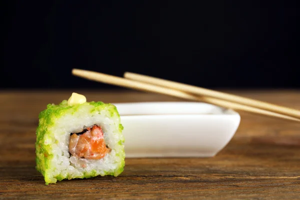 Rouleau avec sauce et bâtons de bois sur fond sombre — Photo