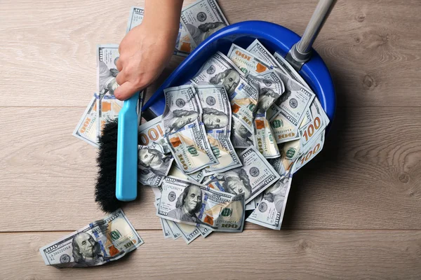 Woman sweeps dollars in garbage scoop