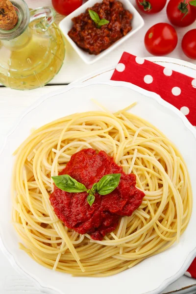 Espaguetis con salsa de tomate y queso en plato blanco, sobre fondo de madera de color — Foto de Stock