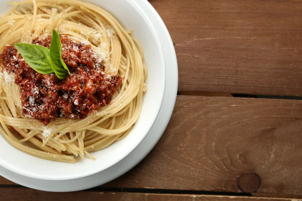 Spaghetti Bolognaise au parmesan dans un bol blanc, sur fond de bois de couleur — Photo