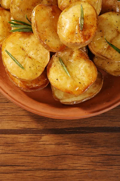 Heerlijke gebakken aardappel met rozemarijn in kom op tafel close-up — Stockfoto