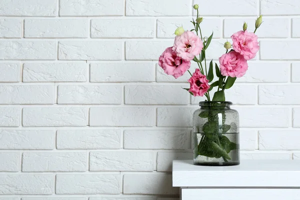 Beautiful flowers in vase on brick wall background — Stock Photo, Image