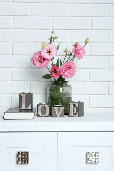 Schöne Blumen in der Vase mit Wort Liebe auf Backsteinmauer Hintergrund — Stockfoto