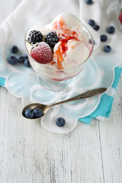 Вкусное мороженое со свежими замороженными ягодами и соусом, на фоне цвета дерева — стоковое фото