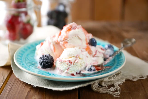 Вкусное мороженое со свежими замороженными ягодами и соусом, на деревянном фоне — стоковое фото
