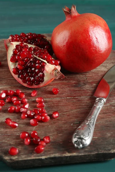 Juicy pomegranate with knife on wooden table, closeup — Stock Photo, Image