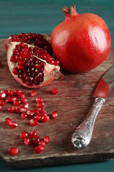 Sappige granaatappel met mes op houten tafel, close-up — Stockfoto