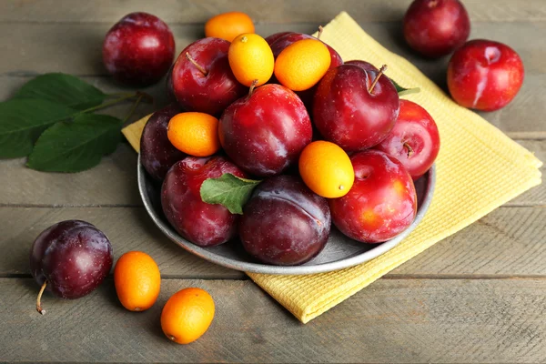 Ripe plums in metal plate on wooden background — Stock Photo, Image