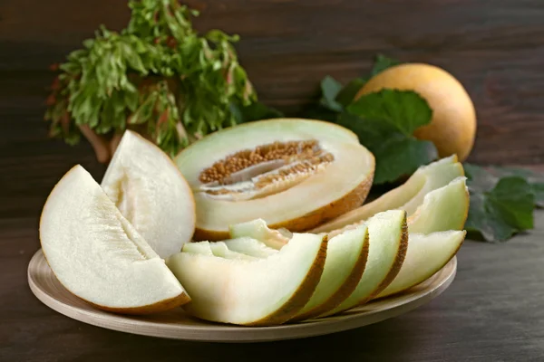 Slices of ripe melons with green leaves on table close up — Stock Photo, Image