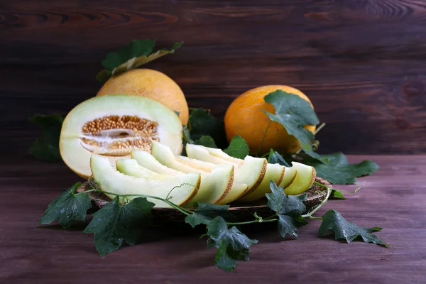 Mogna meloner med gröna blad på trä bakgrund — Stockfoto