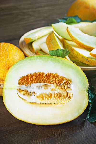 Ripe melons with green leaves on wooden table close up — Stock Photo, Image