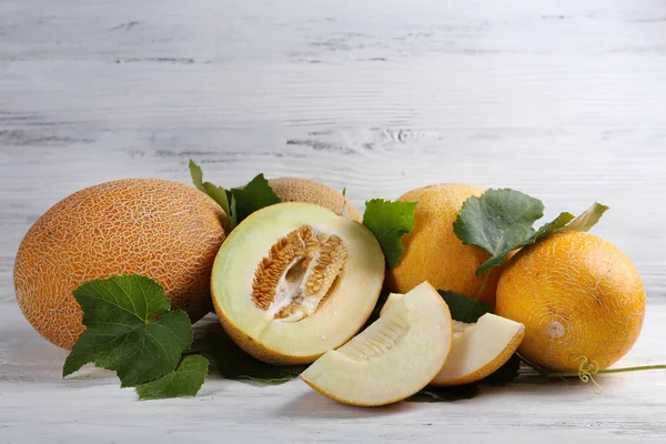 Melones maduros con hojas verdes sobre fondo de madera —  Fotos de Stock