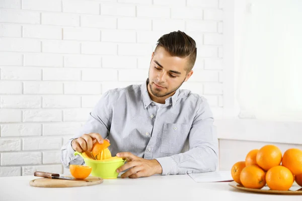 Ung man med citrus-frukt squeezer, förbereda apelsinjuice — Stockfoto