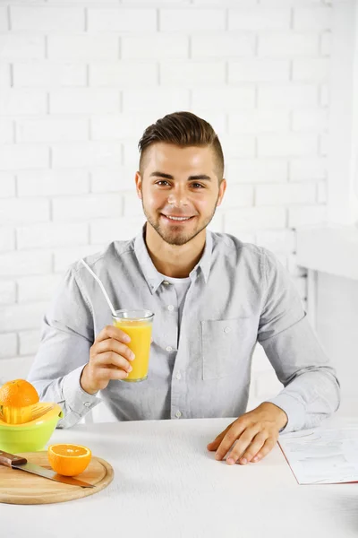 Ung man dricker apelsinjuice — Stockfoto