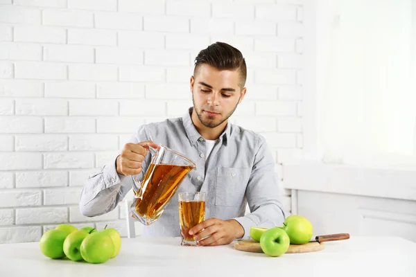 Jeune homme versant du jus de pomme dans du verre — Photo