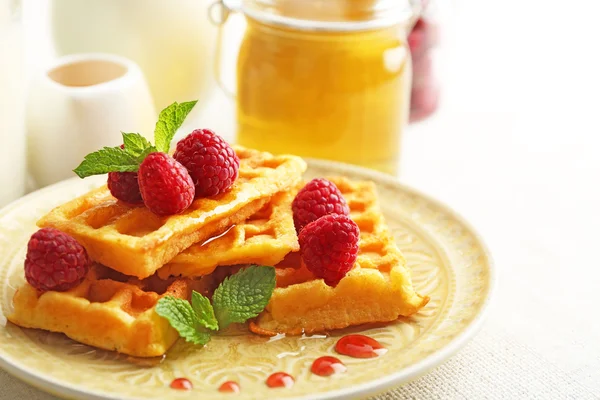Sweet homemade waffles with fresh raspberries on plate, on light background — Stock Photo, Image
