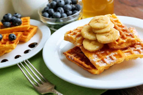 Sweet homemade waffles with sliced banana on plate, on light background — Stock Photo, Image
