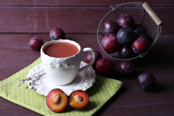 Läckra plommon juice med frukter på träbord nära håll — Stockfoto