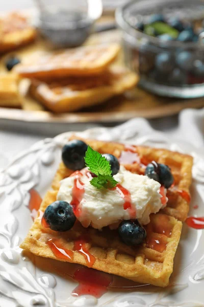 Sweet homemade waffles on plate, on color wooden background — Stock Photo, Image