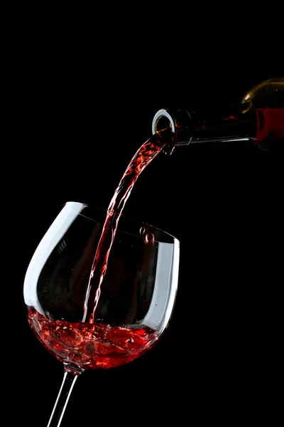 Red wine pouring into wine glass on black background — Stock Photo, Image