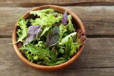 Ahşap masa üzerinde kase taze karışık yeşil salata yakın çekim
