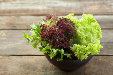 Ahşap masa üzerinde kase taze karışık yeşil salata yakın çekim