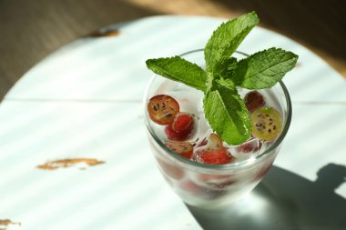 Bir bardak soğuk, ferahlatıcı yaz içeceği. Masada böğürtlen ve buz var.