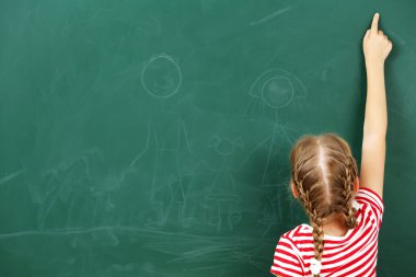 Küçük kız kara tahta bir şeye işaret