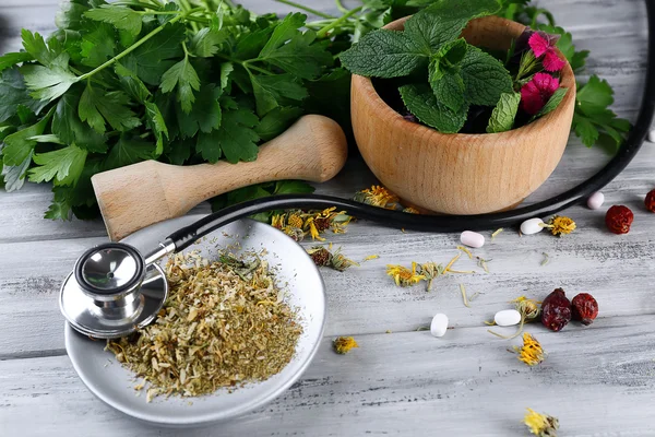 Medicina alternativa hierbas, bayas y estetoscopio sobre fondo de mesa de madera — Foto de Stock