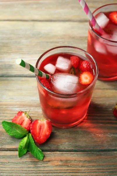 Los vasos del jugo de fresa con las bayas sobre la mesa se acercan —  Fotos de Stock