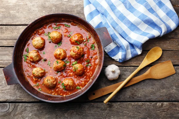 Сковородка с мясом в томатном соусе, на деревянном фоне — стоковое фото