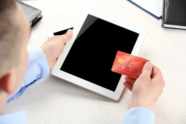 Ember tartja a hitelkártya és a tabletta a munkahelyi háttér — Stock Fotó