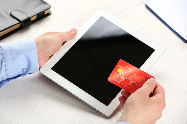 Man holding credit card and tablet on workplace background — Stock Photo, Image