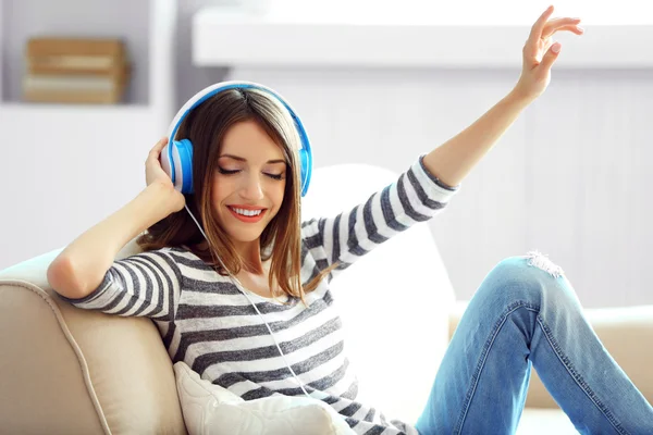 Vrouw die muziek luistert in hoofdtelefoon in de kamer — Stockfoto