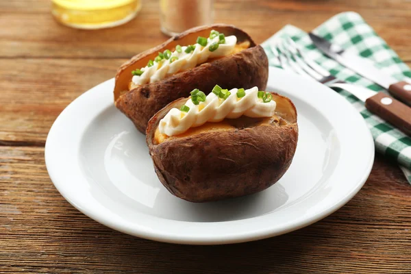 Baked potato mayonnaise and chives in white plate on wooden table, closeup — Stock Photo, Image