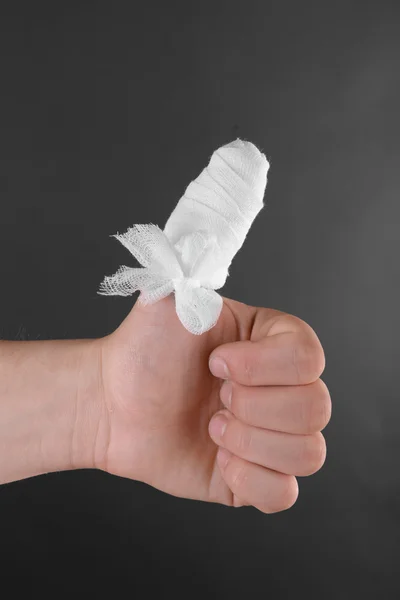 Injured bandaged finger on dark background — Stock Photo, Image