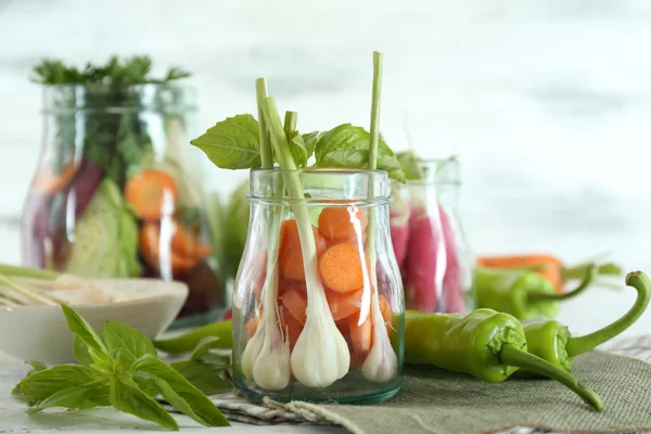 Friss zöldségek, üvegek, a táblázat a fény elmosódott háttér — Stock Fotó