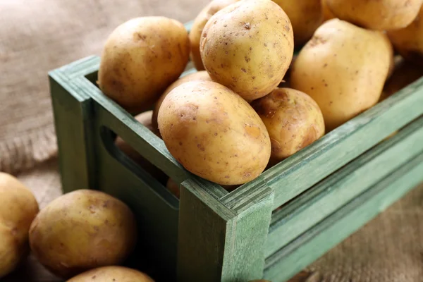 Batatas jovens em caixa na mesa de perto — Fotografia de Stock