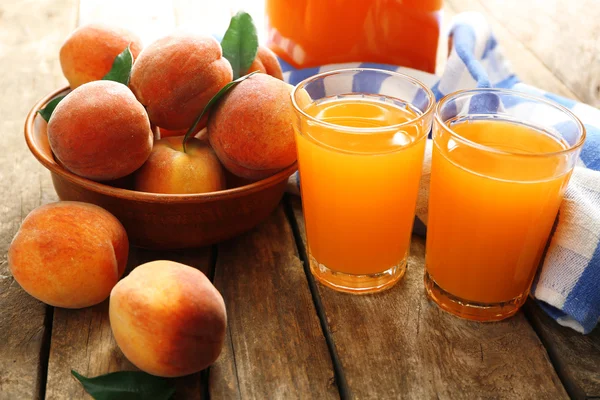 Ripe peaches and juice in glass on wooden background — Stock Photo, Image