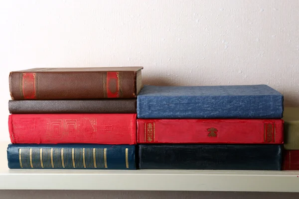 Vecchi libri su scaffale, primo piano, su sfondo parete leggera — Foto Stock