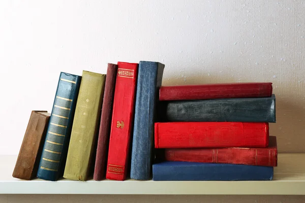 Gamle bøker på hylla, nærme, på lys veggbakgrunn – stockfoto